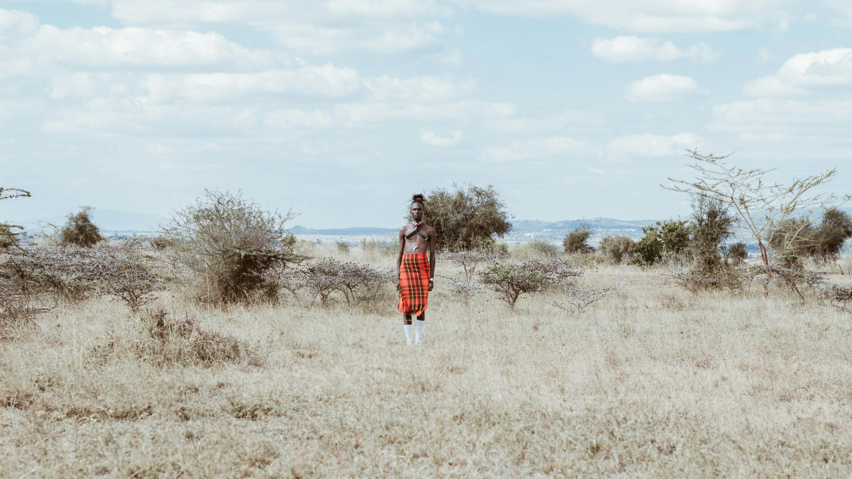 Masai guide standing in open wilderness during golden light in Kenya.