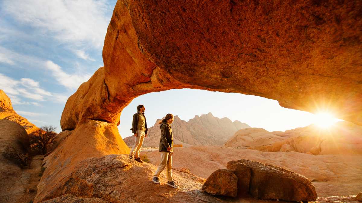 People walking along a tall dune at sunrise in Sossusvlei, Namibia.