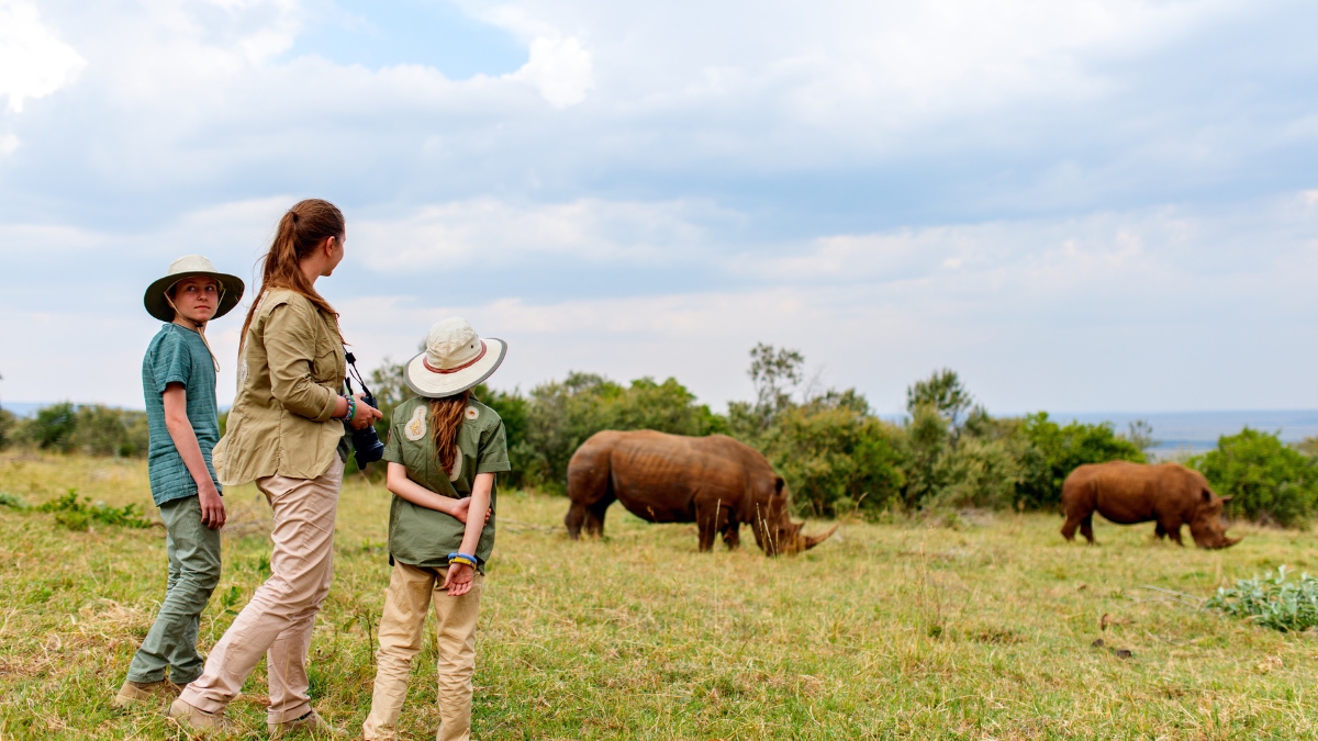 Guests walking behind a guide across open grass during a morning walking safari.