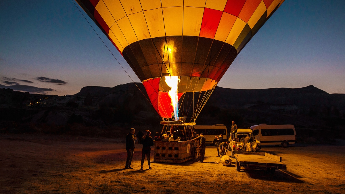 Hot air balloon rising over open plains at sunrise during a safari.
